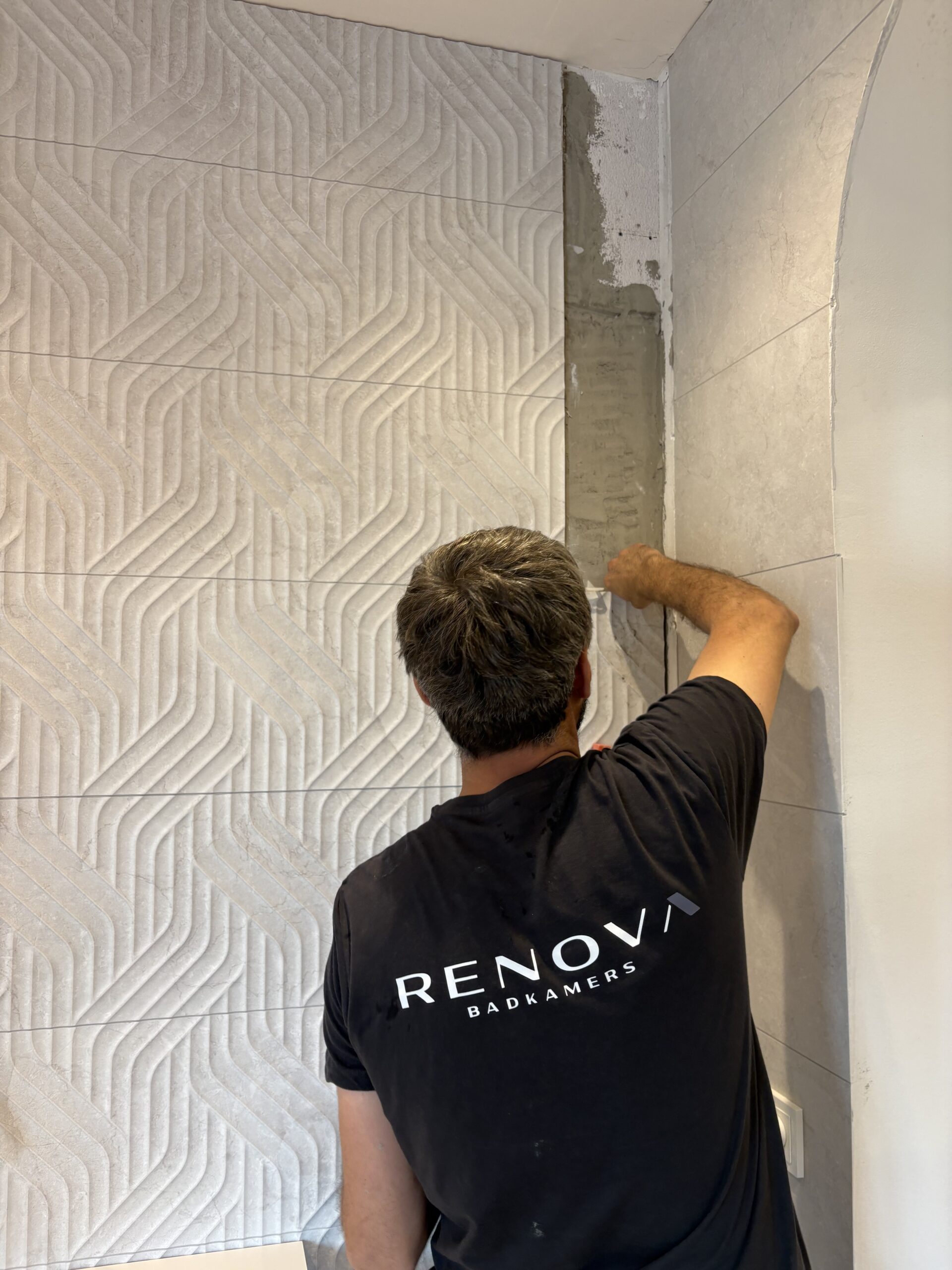 Tegelzetter van Renova Badkamers plaatst reliëftegels op een badkamerwand