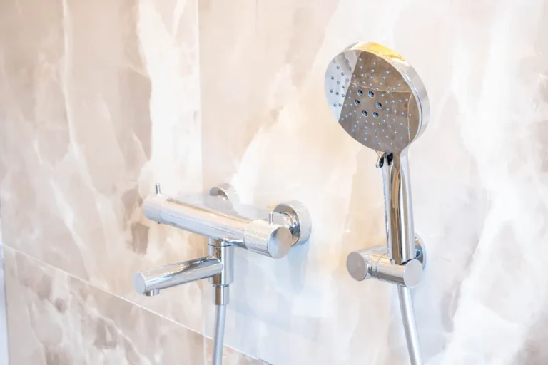 Chromen thermostatische badkraan met handdouche op beige marmerlook wandtegels