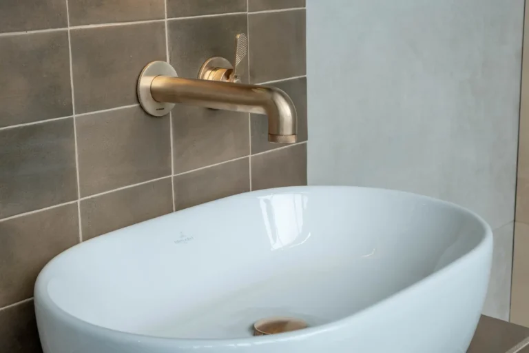 Inbouwkraan in geborsteld brons boven een witte opzetwaskom in de Renova badkamershowroom