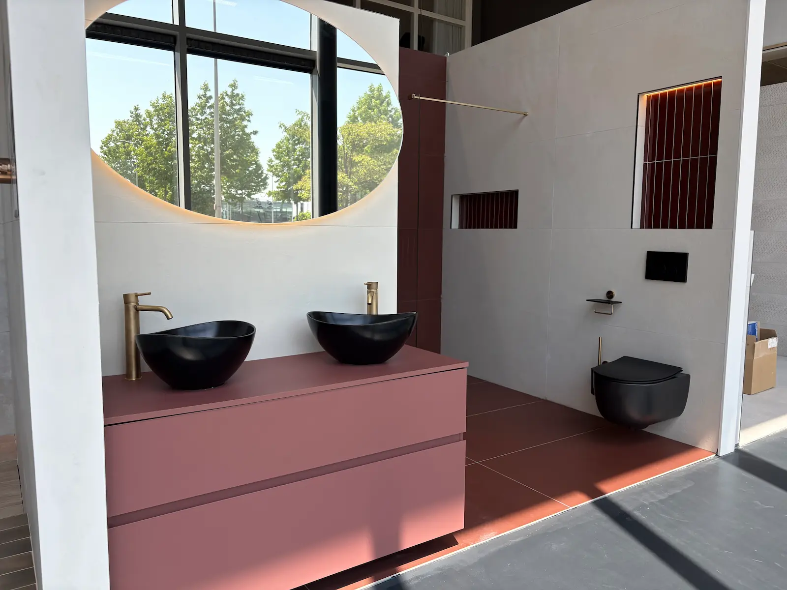 Badkameropstelling met roze badmeubel, twee zwarte waskommen en zwart toilet