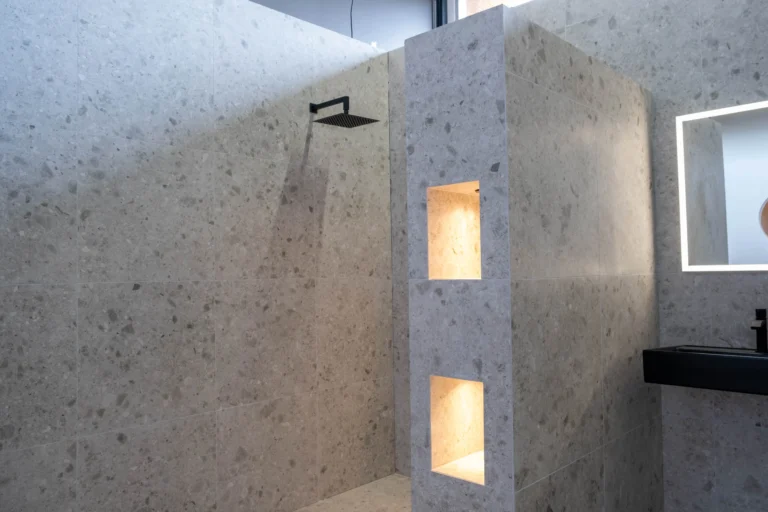 Terrazzolook inloopdouche met zwarte regendouche en verlichte wandnissen in de Renova badkamershowroom
