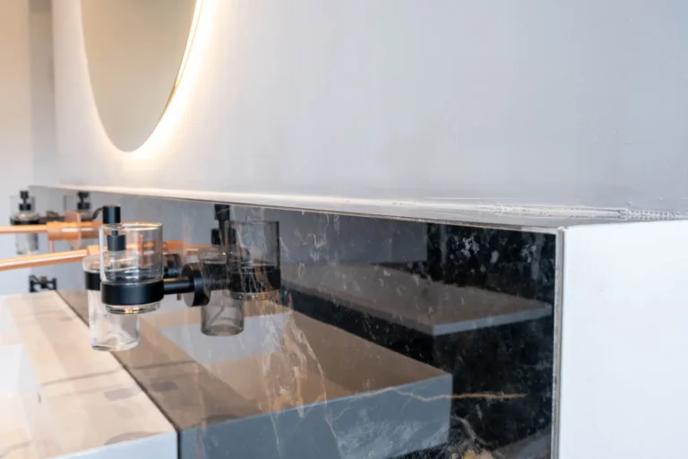 Detail van zwart marmerlook tegelwerk met luxe badkameraccessoires in de Renova badkamershowroom