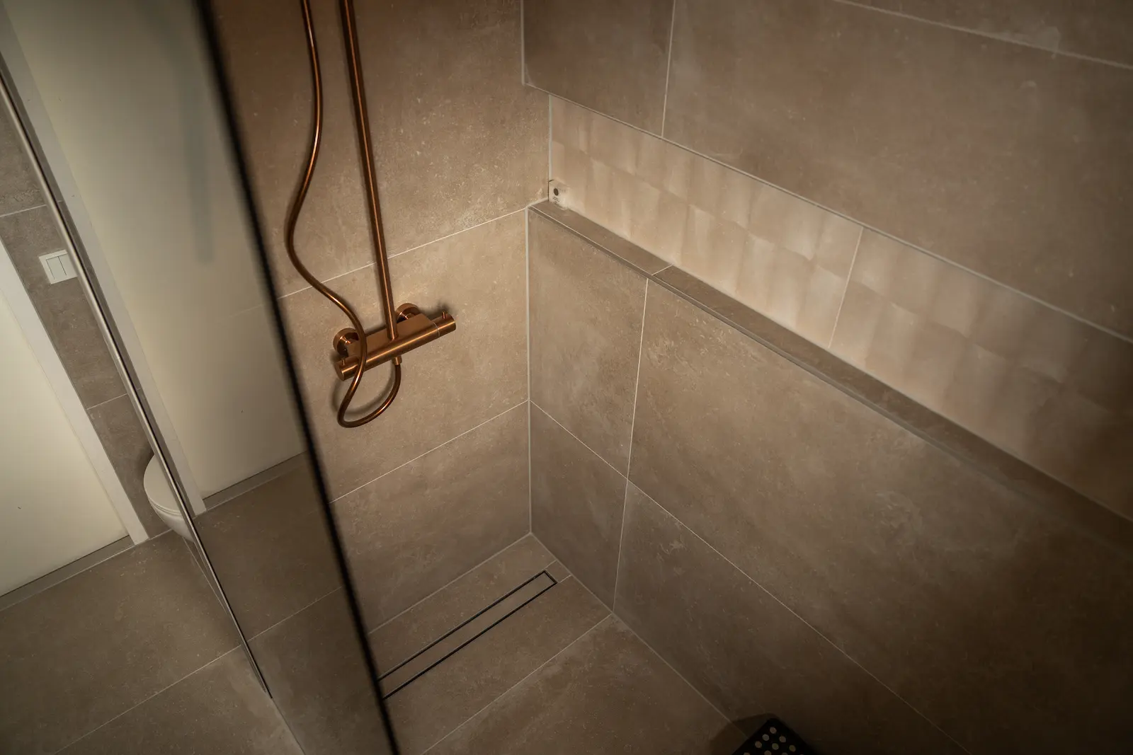 Inloopdouche met bronskleurig glas, ingebouwde douchenis en koperen douche in Spijkenisse