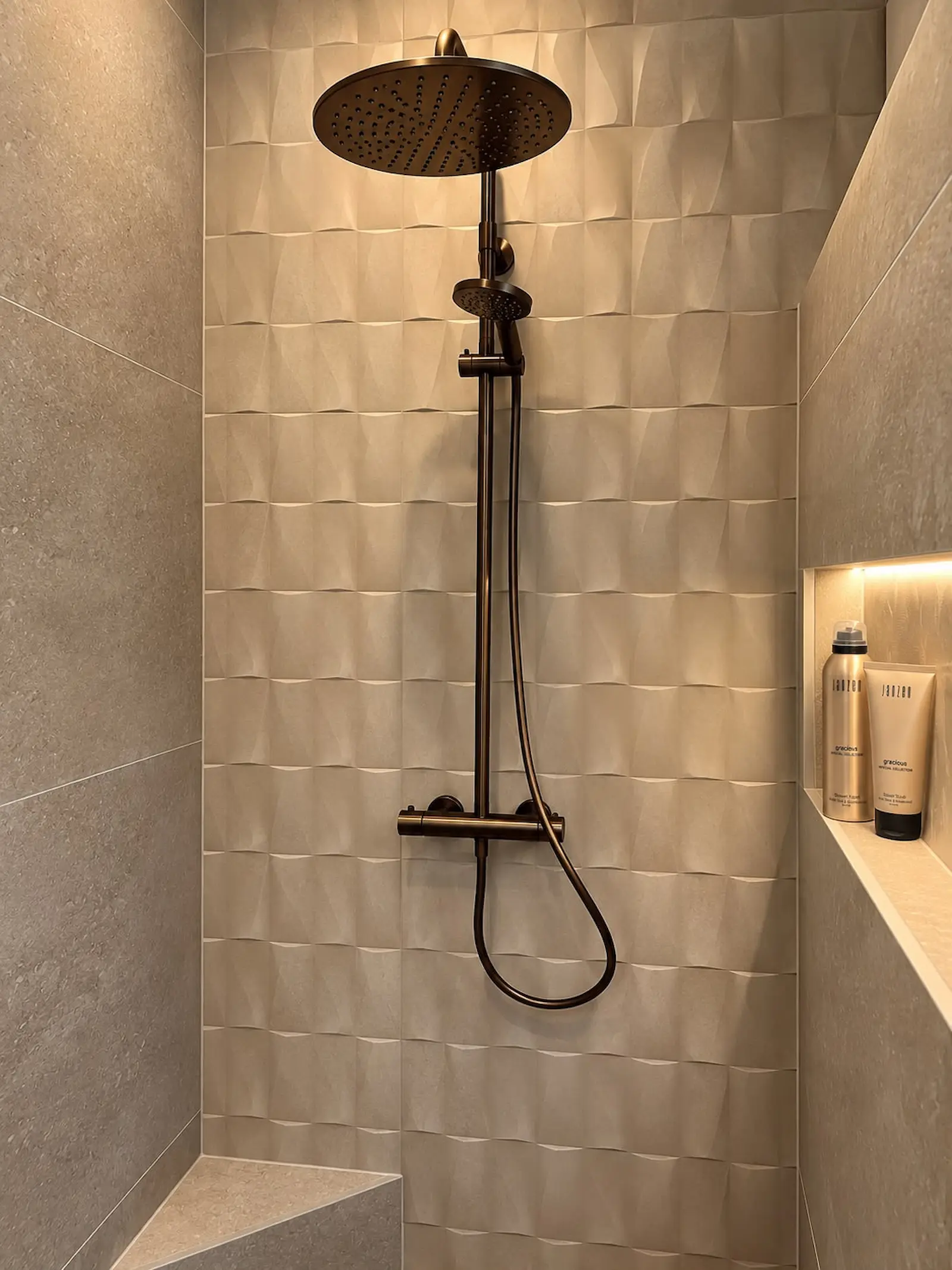 Inloopdouche in gerenoveerde badkamer in Rotterdam met beige wandtegels, nisverlichting en bronzen regendouche