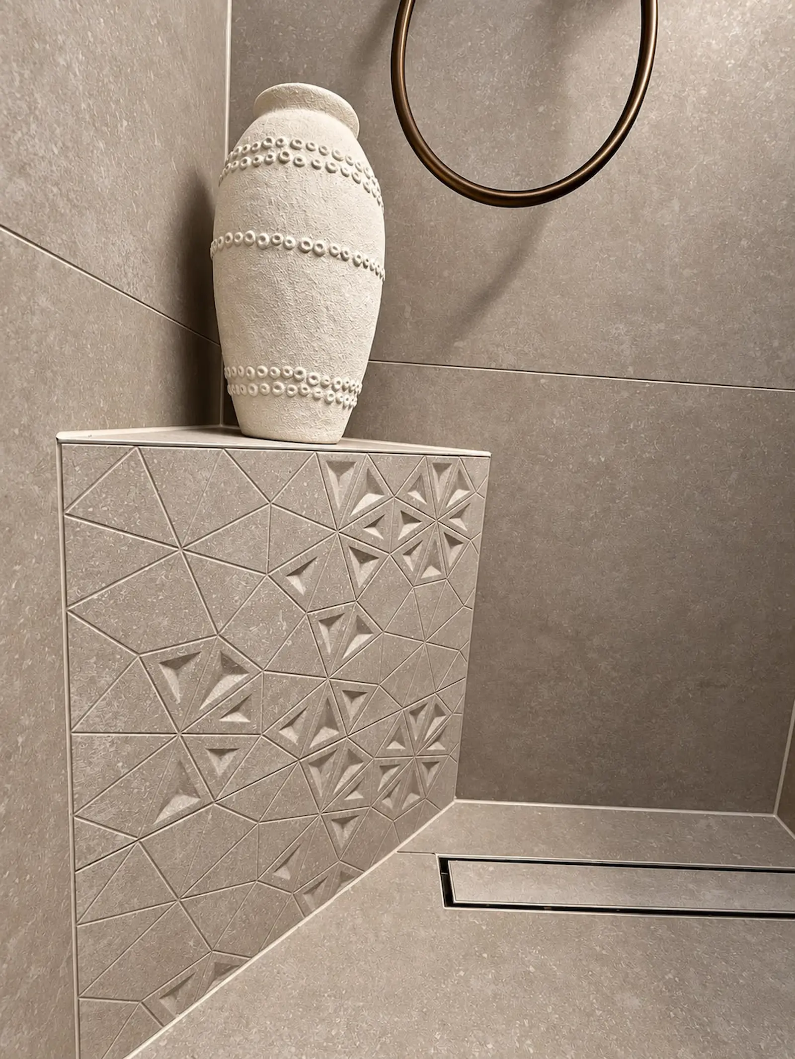 Maatwerk hoekzitbankje met decoratieve tegels en douchegoot in badkamer in Rozenburg