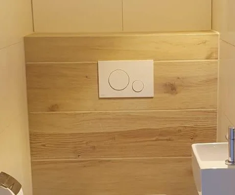 Witte drukplaat van het inbouwreservoir op de houtlook achterwand van het toilet